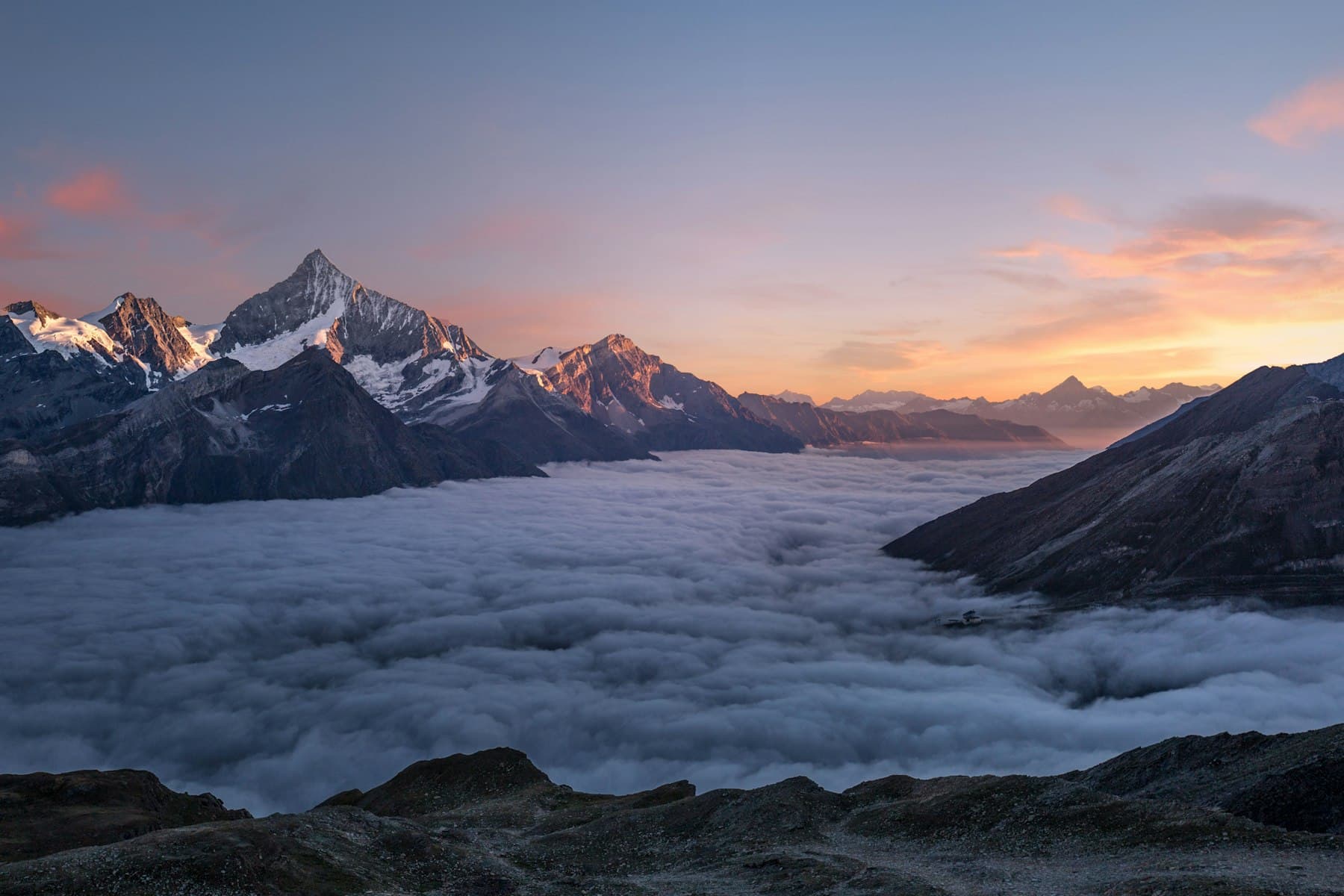 Snow-capped peaks rising above a sea of cloud, in the spirit of a high pass above Ala-Kul